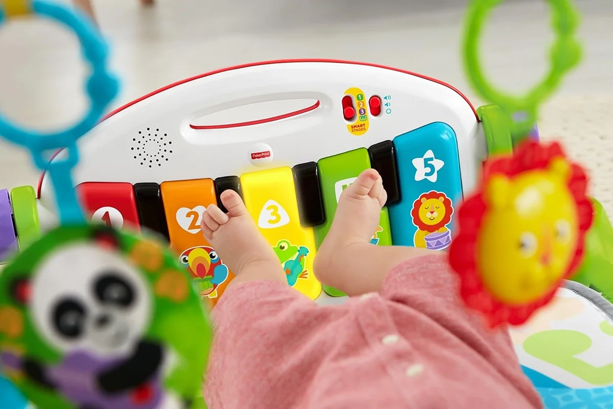 Baby kicking the numbered light-up piano keys of the Fisher-Price Deluxe Kick & Play Piano Gym
