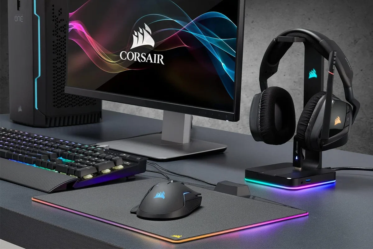 Corsair ST100 RGB stand holding a headset on a desk beside a monitor, keyboard and mouse