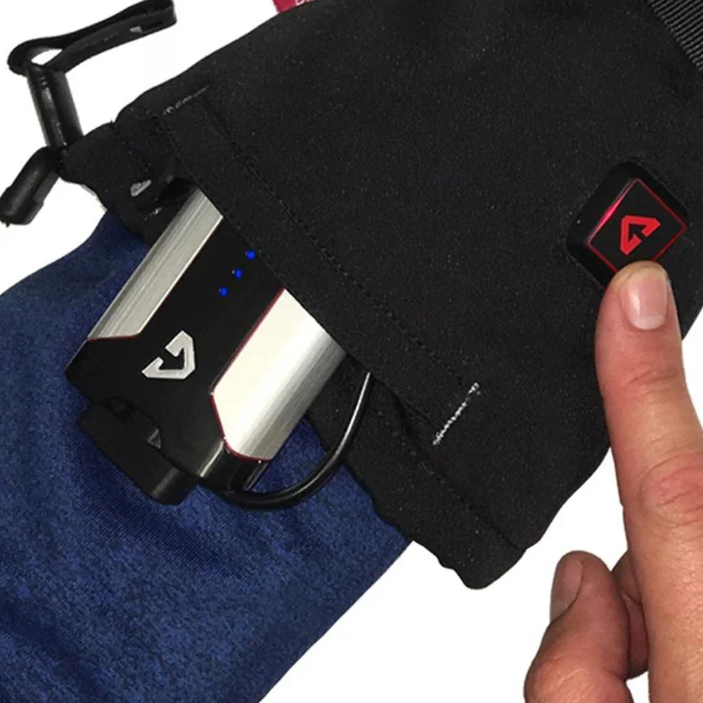 Close-up of a Gerbing S7 gauntlet with a 7V battery pack sliding into the cuff pocket as a finger presses the heat control button