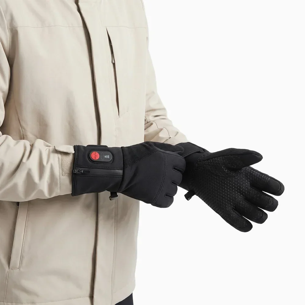 Savior Heat SW04 heated glove liners worn on both hands with a winter jacket, showing the cuff controller and zipper on one glove and the anti-slip palm on the other