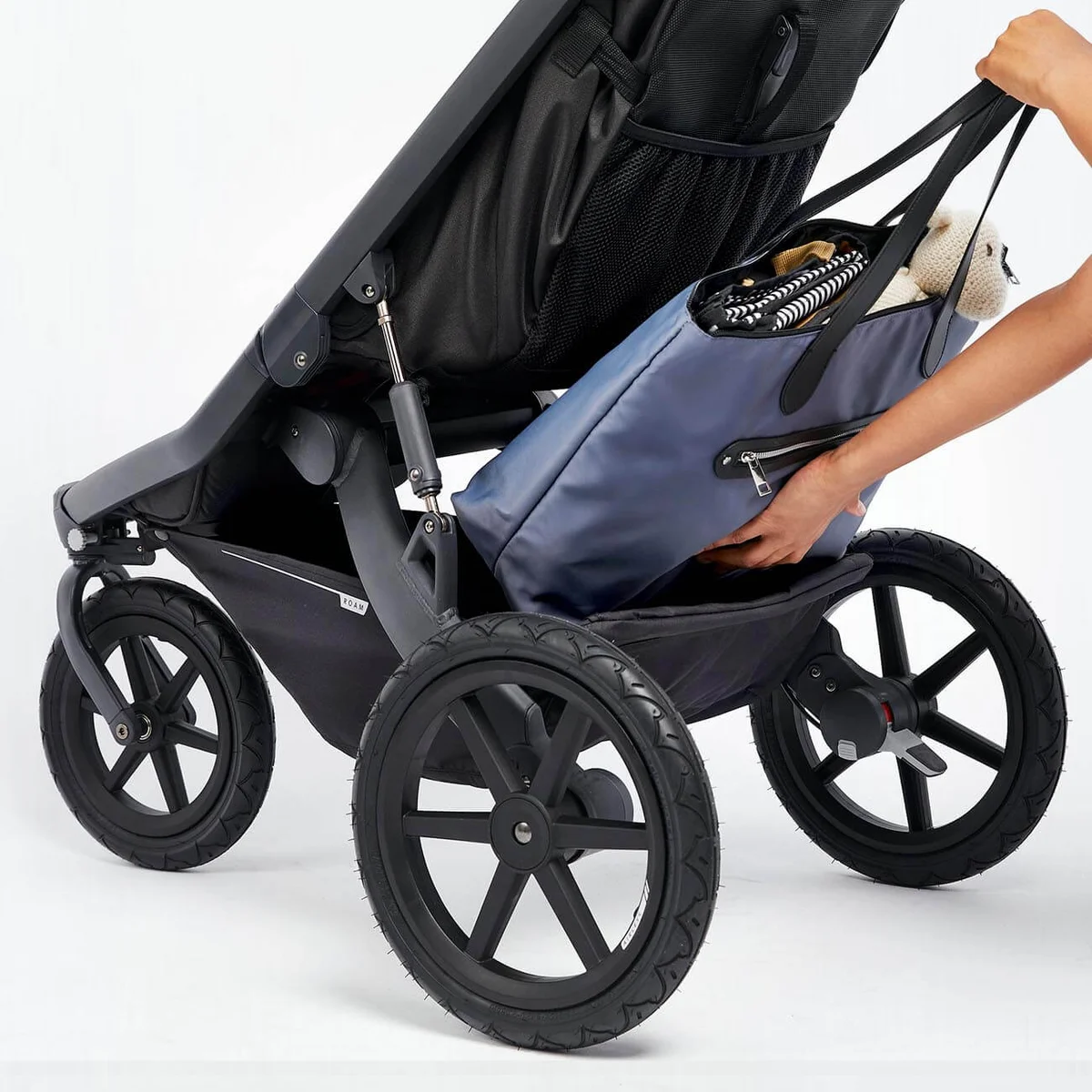 Guava Roam Crossover storage basket with diaper bag being loaded underneath