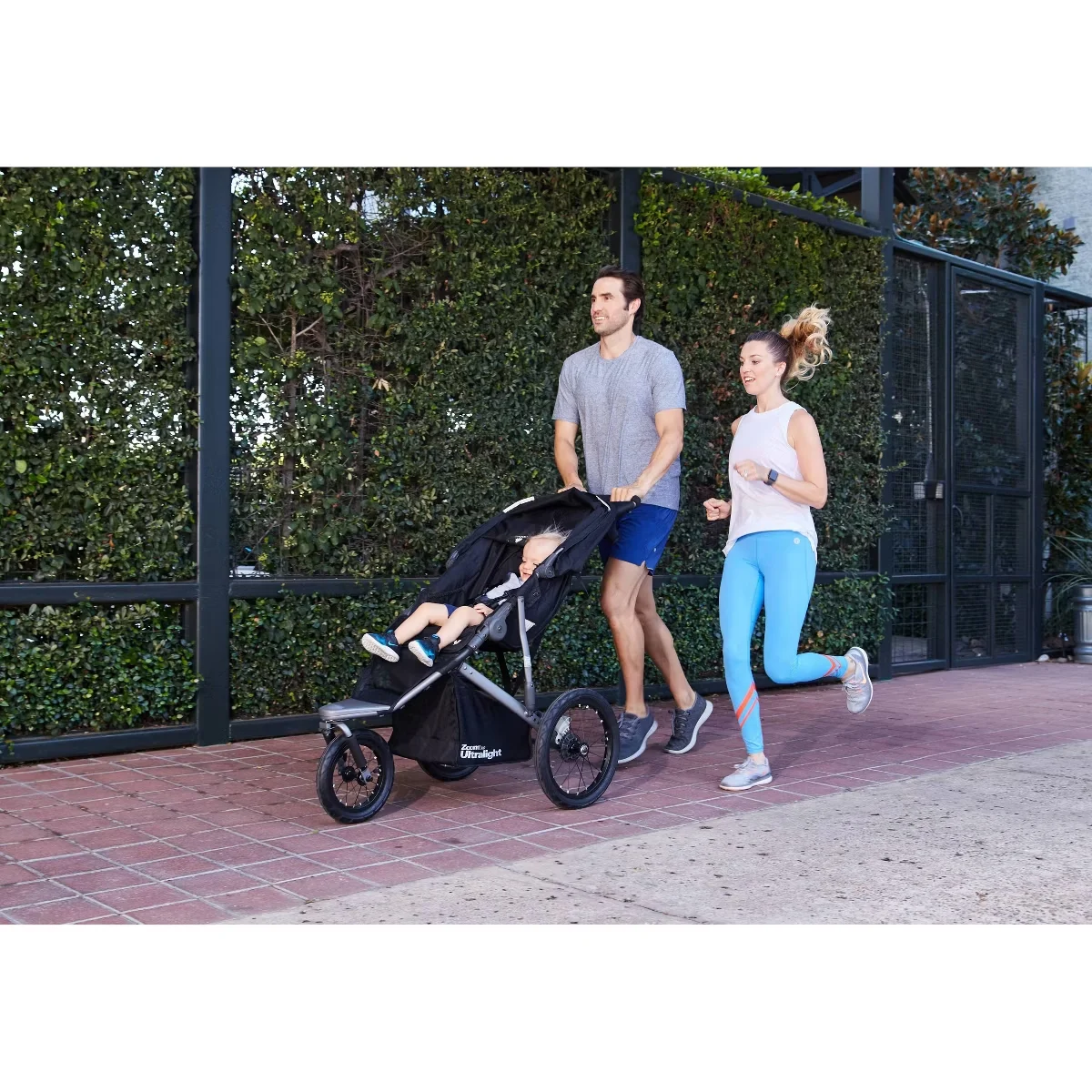 Couple jogging outdoors with the Joovy Zoom 360 Ultralight stroller and toddler
