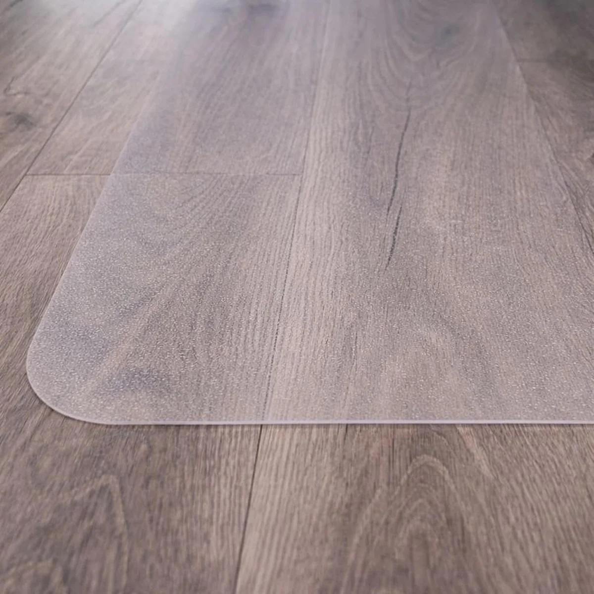 Rounded corner of the Marvelux transparent polycarbonate mat lying flat on wood-look flooring