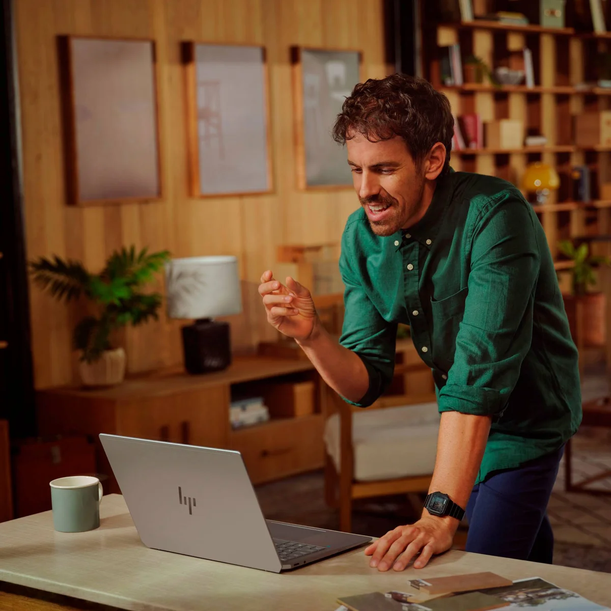 Man leaning over desk working on HP OmniBook Ultra, showing the silver HP logo lid