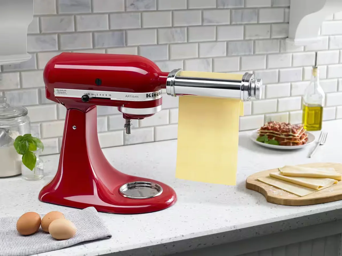 KitchenAid Artisan mixer with pasta roller attachment rolling fresh lasagna sheets in kitchen setting