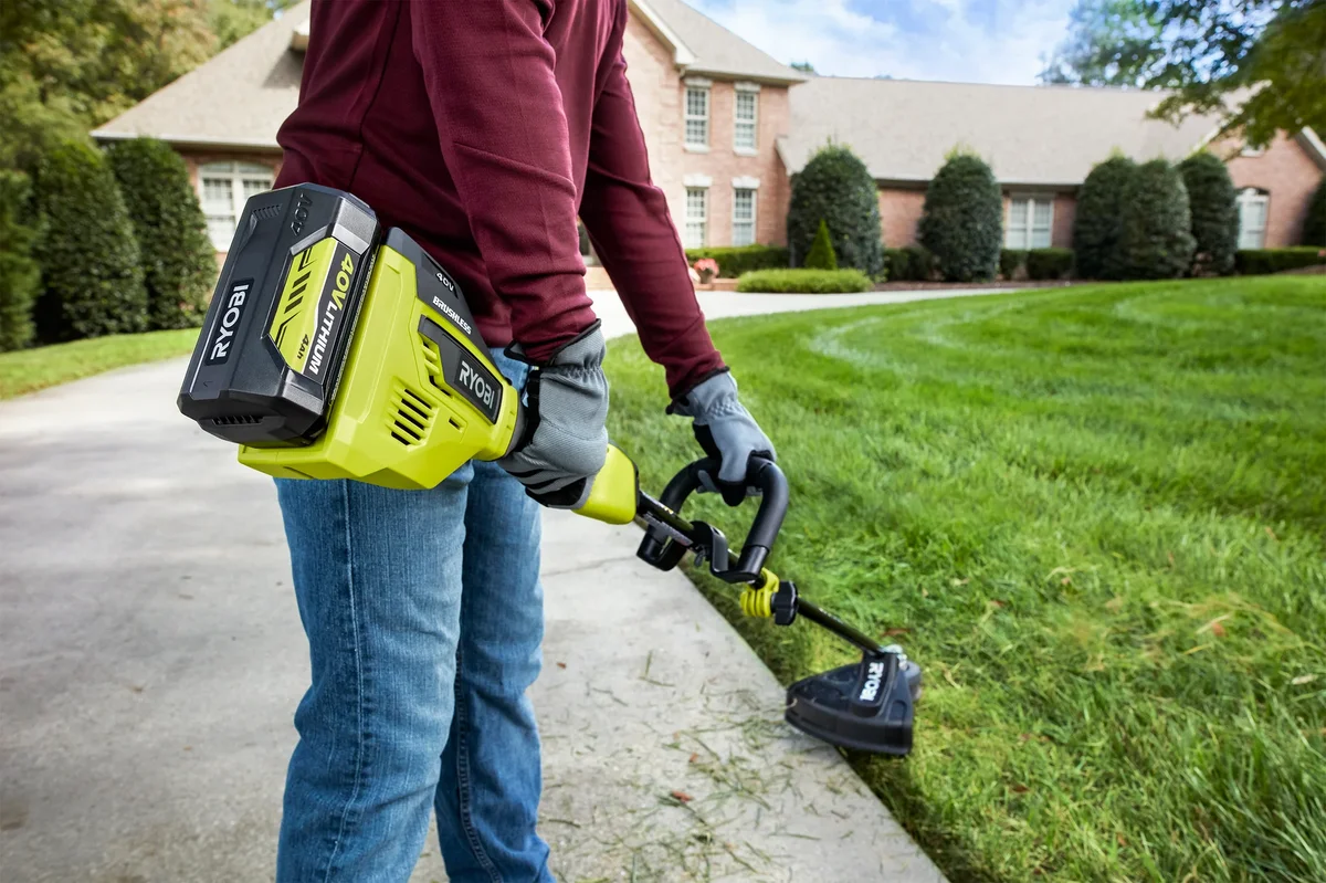 Ryobi 40V string trimmer in use trimming lawn edge near driveway