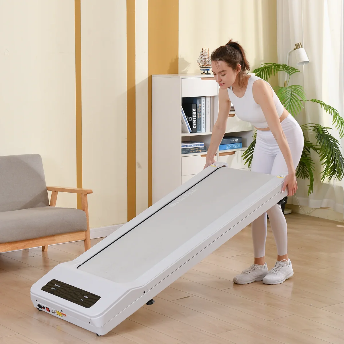 Person transporting the LifeSpan TX6-GlowUp treadmill by tilting it upright on its wheels