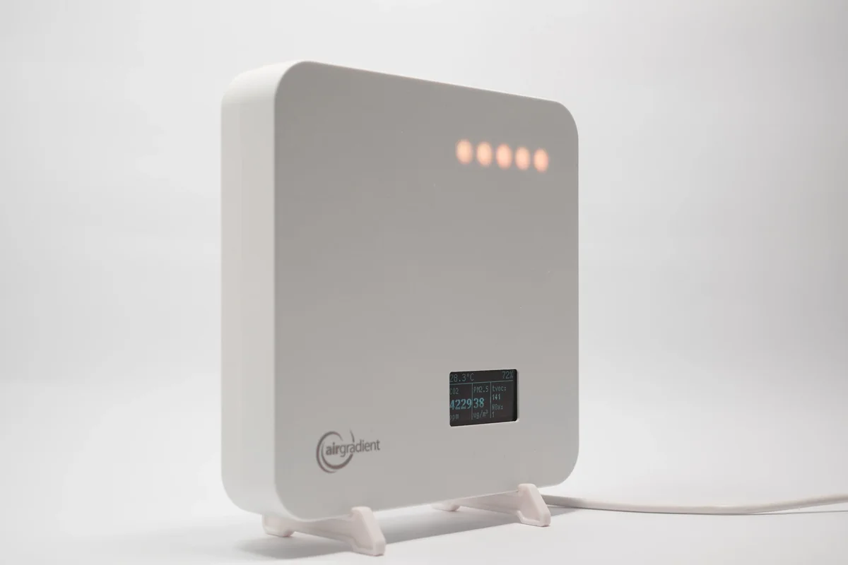 AirGradient One monitor three-quarter side angle on its stand, showing the slim white enclosure and OLED display