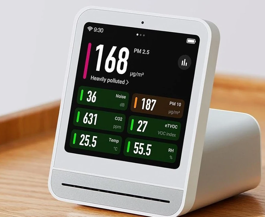 Qingping Air Monitor 2 on a wood desk showing the PM2.5 air quality dashboard