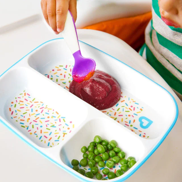 Close-up of toddler using Munchkin Splash divided plate with pureed food and peas