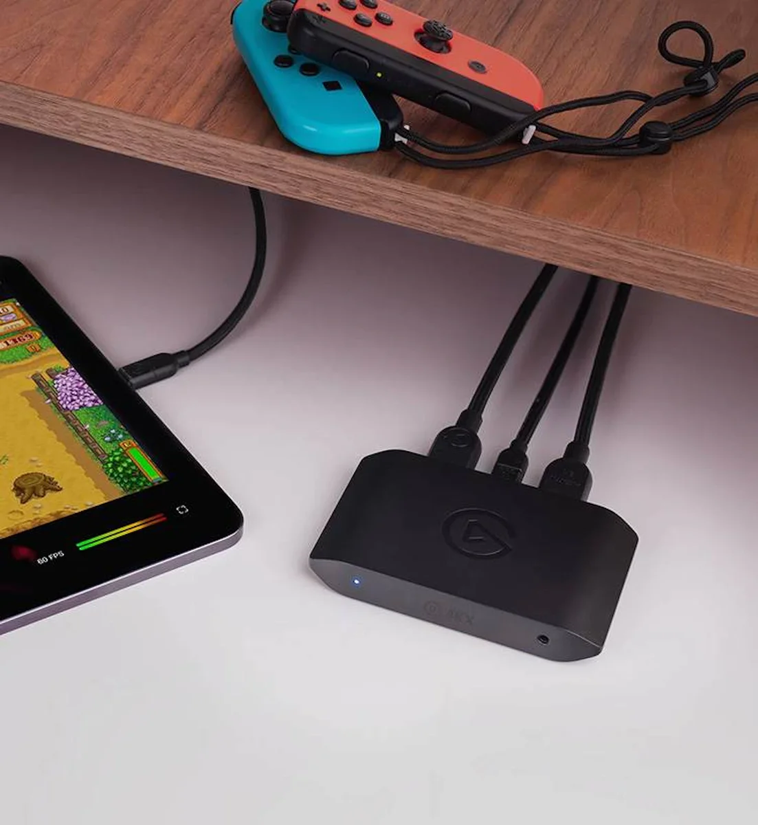 Elgato Game Capture 4K X in use under a desk with HDMI and USB-C cables connected, capturing Nintendo Switch gameplay to a tablet