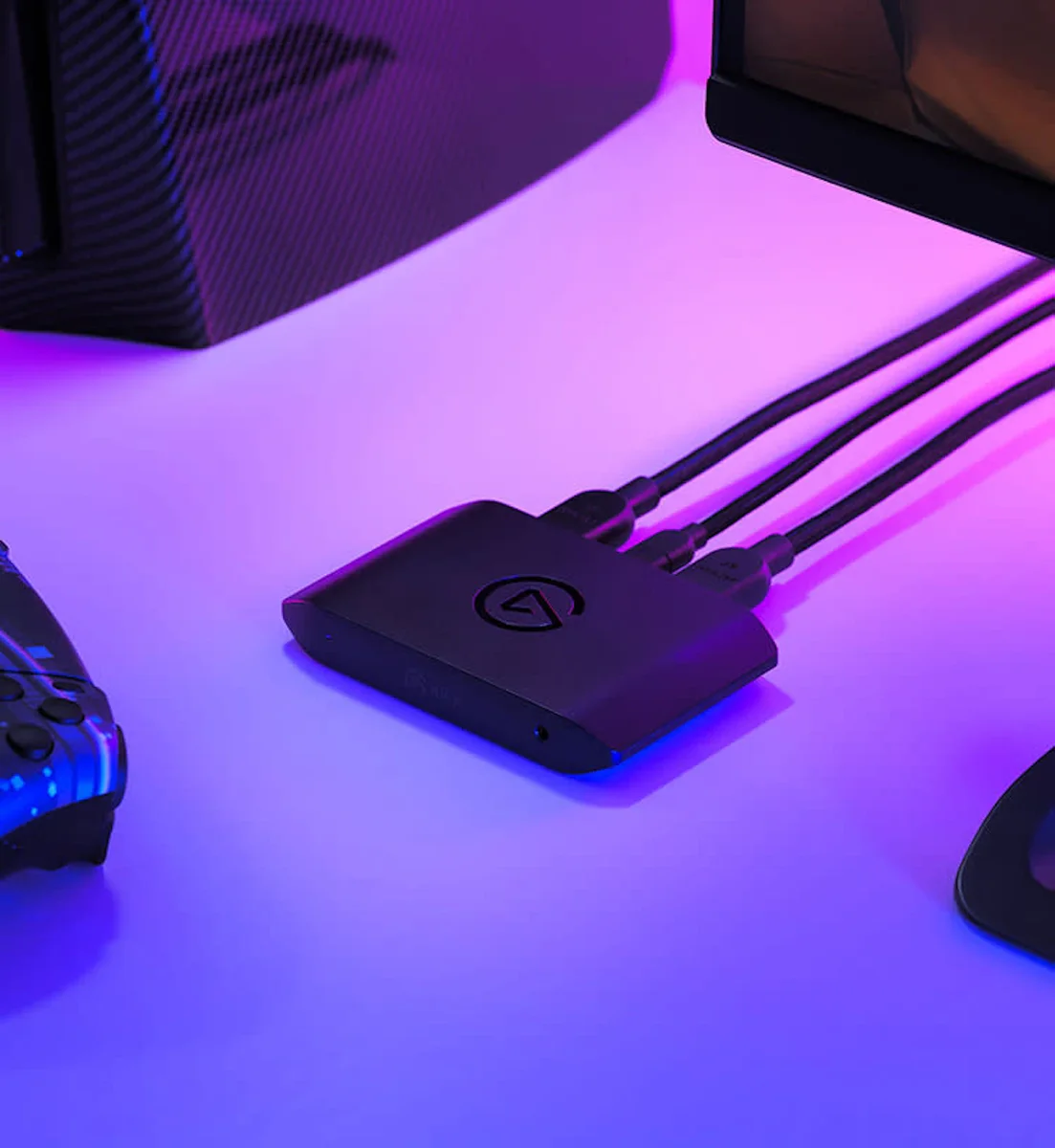 Elgato Game Capture 4K X on a gaming desk with cables connected, lit by purple RGB lighting beside a controller and monitor