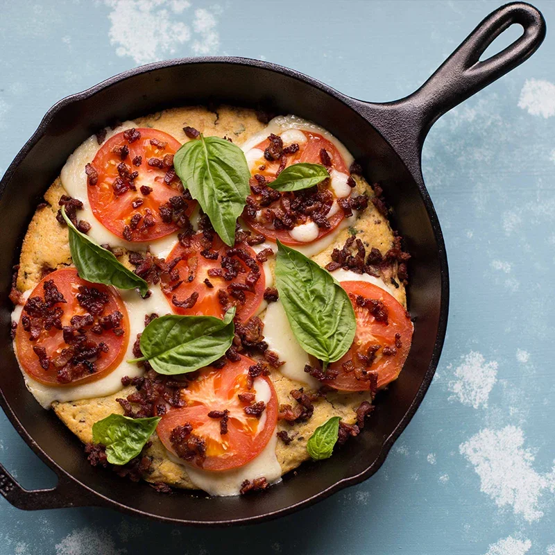 Lodge Classic 10.25-inch cast iron skillet in use, baking a tomato, mozzarella, and basil flatbread