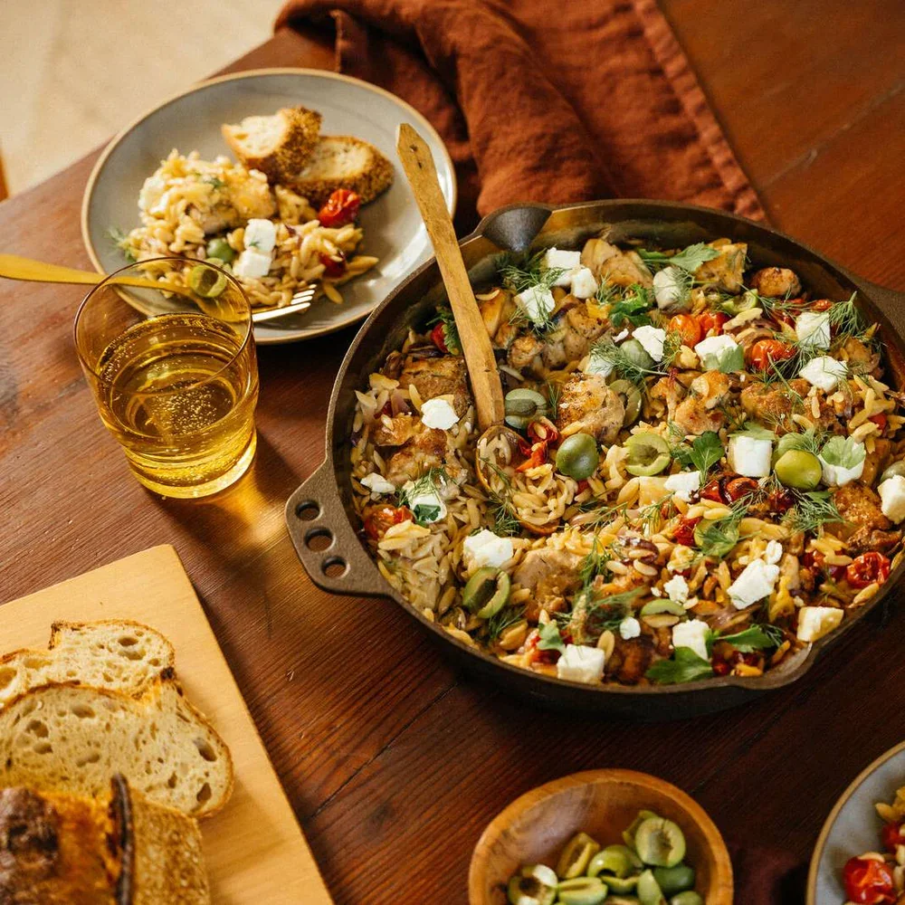 Smithey No. 12 skillet in use on a table, filled with a baked orzo and chicken dish