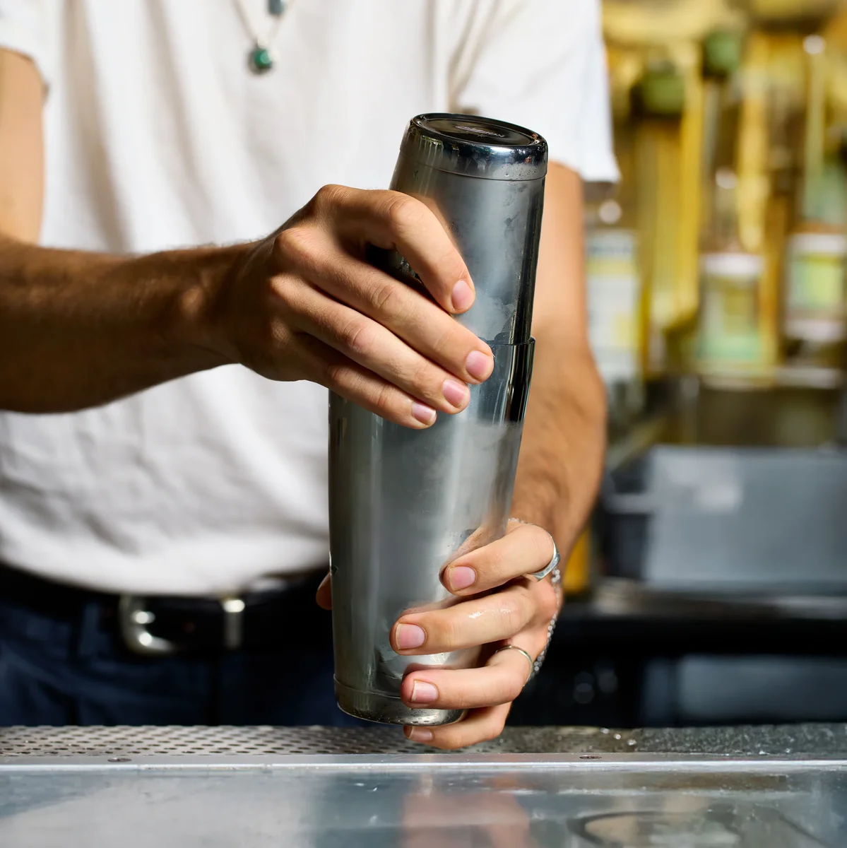 Bartender shaking a drink in frosted Koriko tins behind a bar