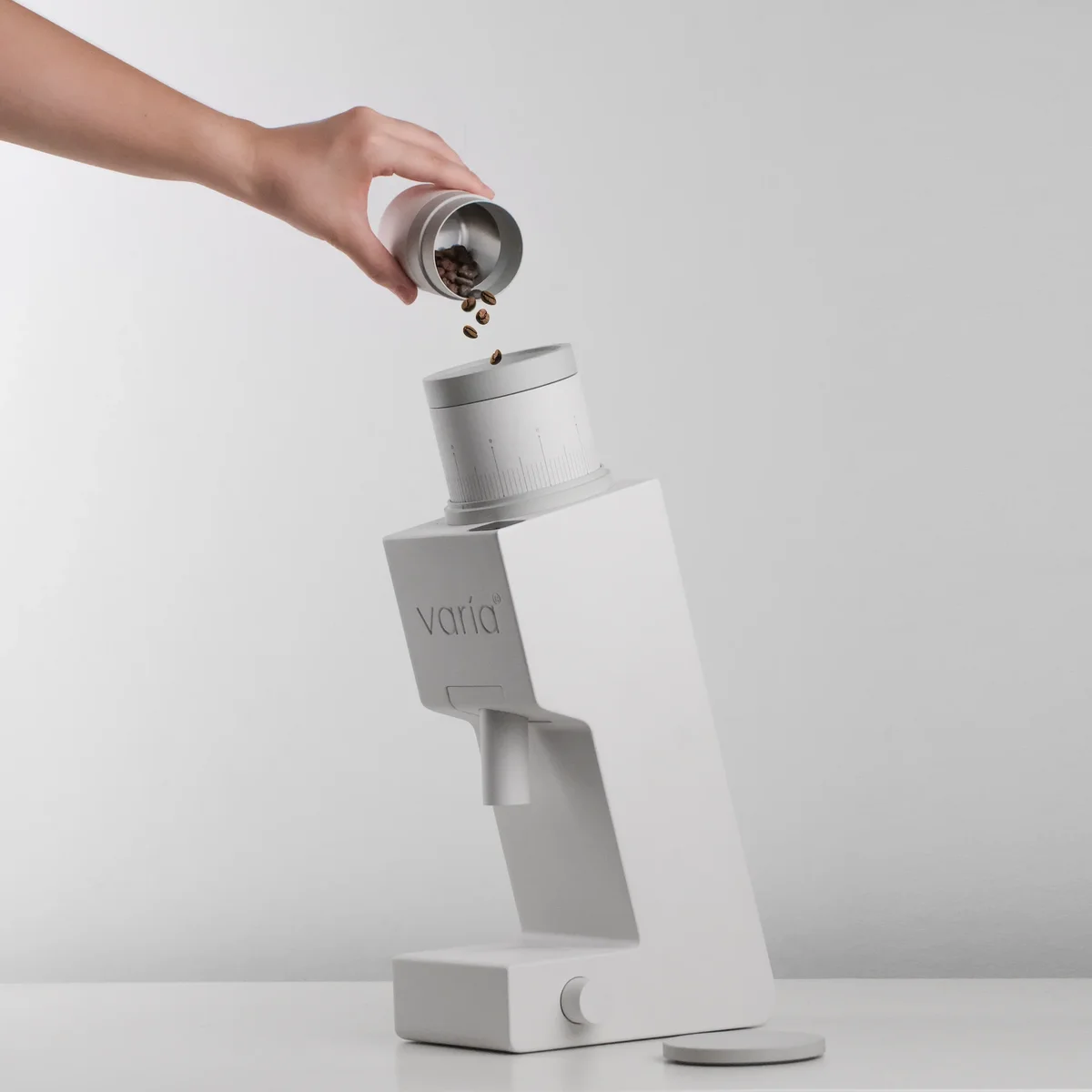 Hand single-dosing coffee beans into the Varia VS6 grinder, lifestyle in-use shot