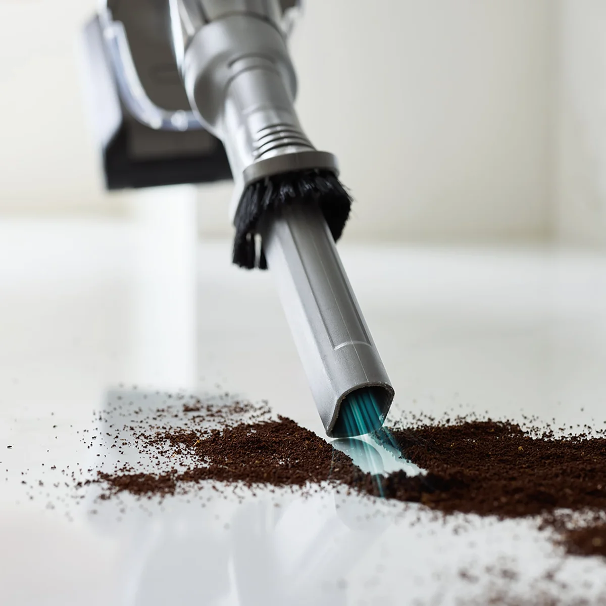 Close-up of the Shark PowerDetect Clean & Empty duster crevice tool picking up coffee grounds from a hard floor