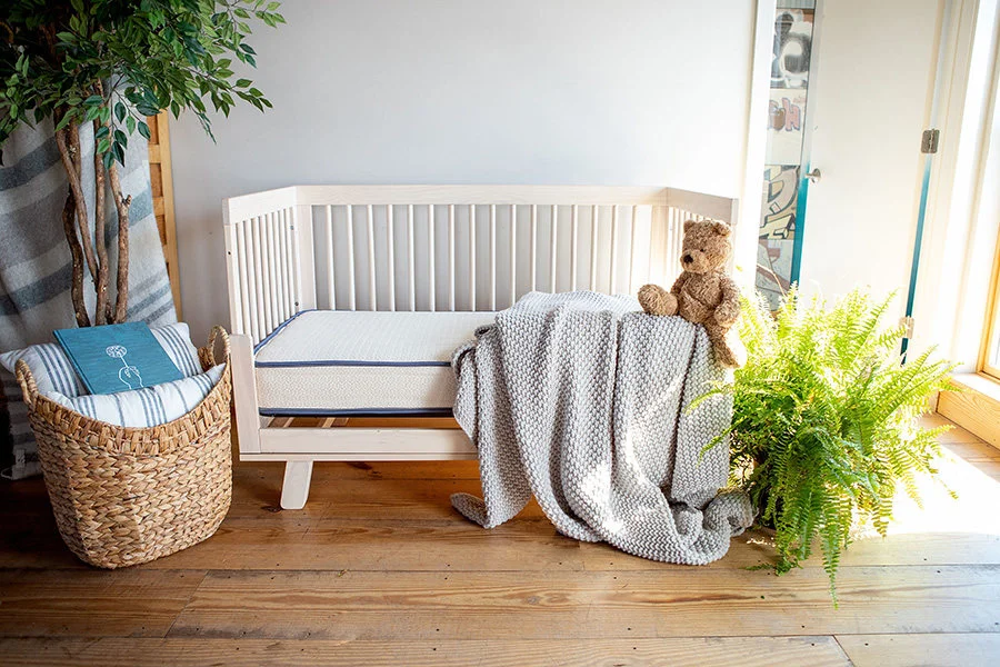 My Green Mattress Emily displayed in a natural wood crib in a warm nursery setting