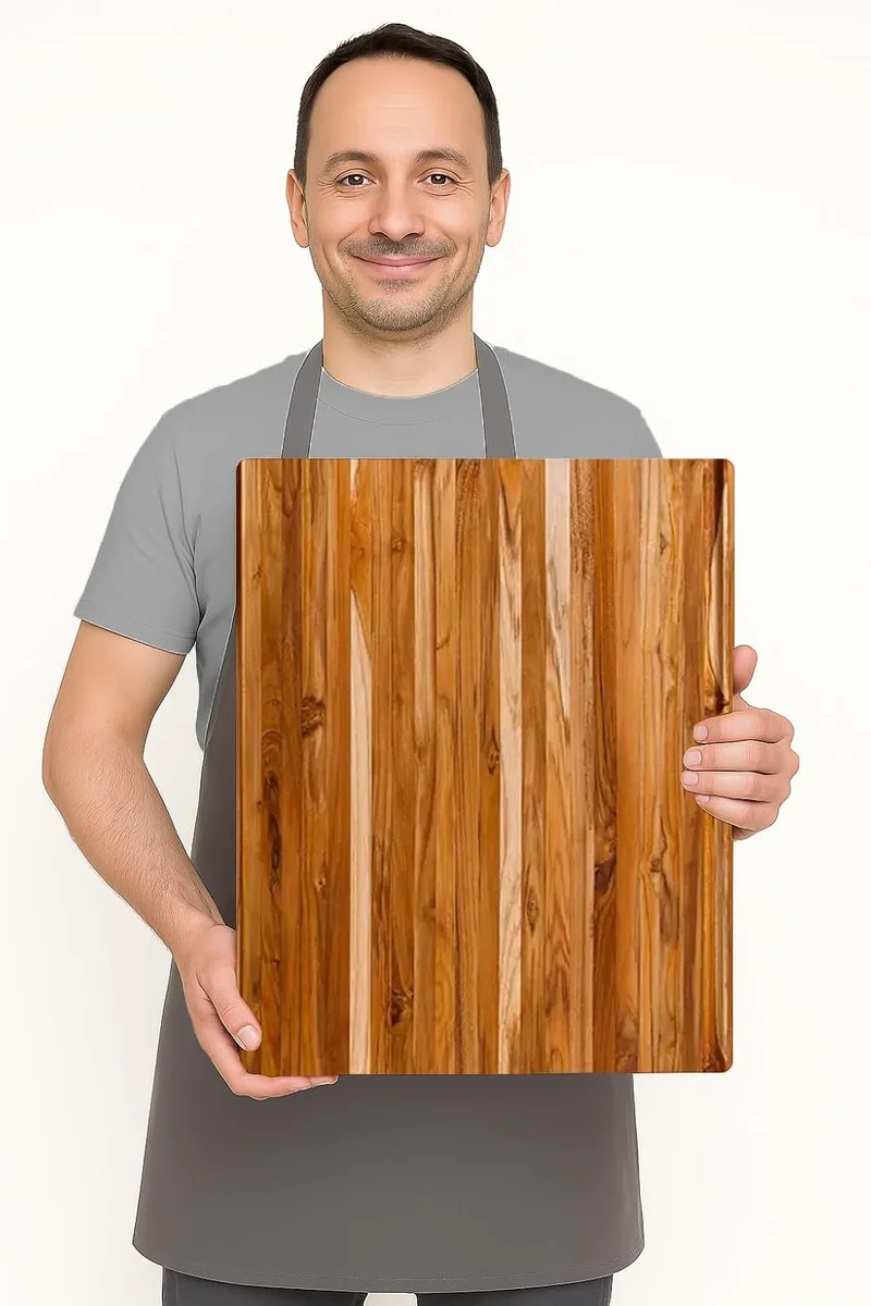 A person holding up the Teakhaus Extra-Large Professional Cutting Board to show its size relative to a person's torso