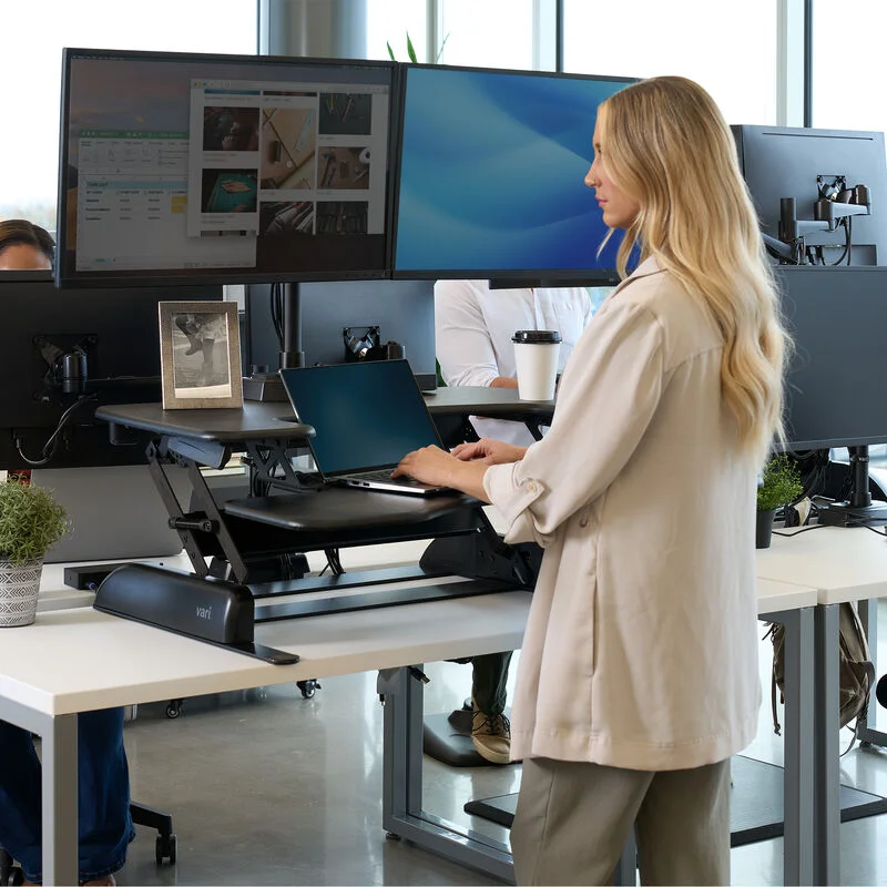 Person standing and working at a VariDesk Pro Plus 36 converter in an open office environment