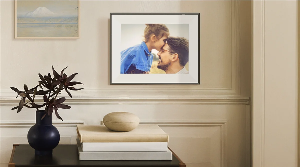 Aura Ink frame wall-mounted in a living room displaying a family portrait