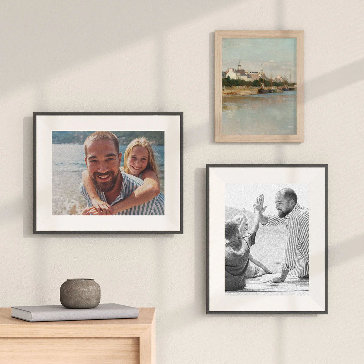 Three Aura Ink frames displayed on a wall and shelf showing family photos