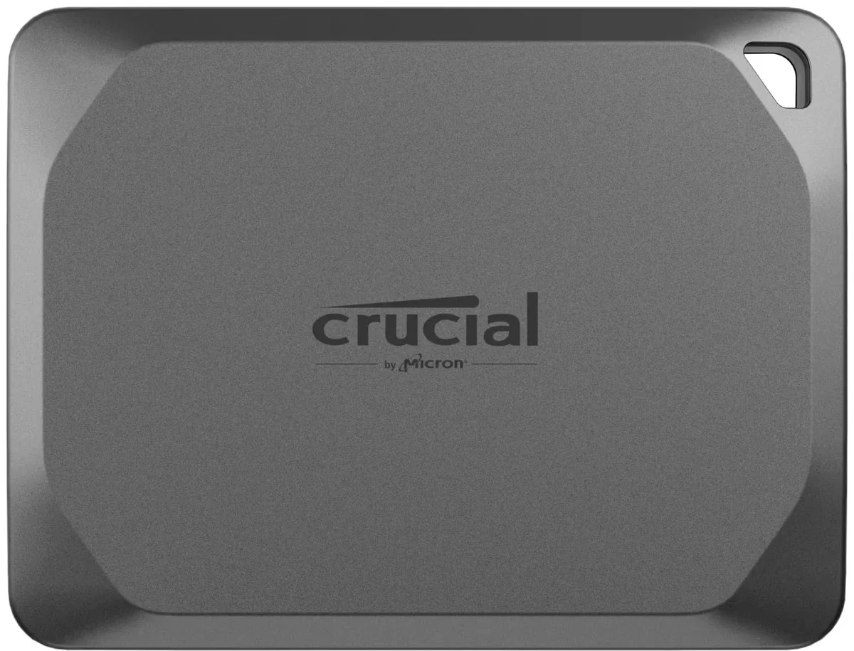 Crucial X9 Pro portable SSD in space gray, top-down view showing the credit-card-sized aluminum body and corner lanyard hole