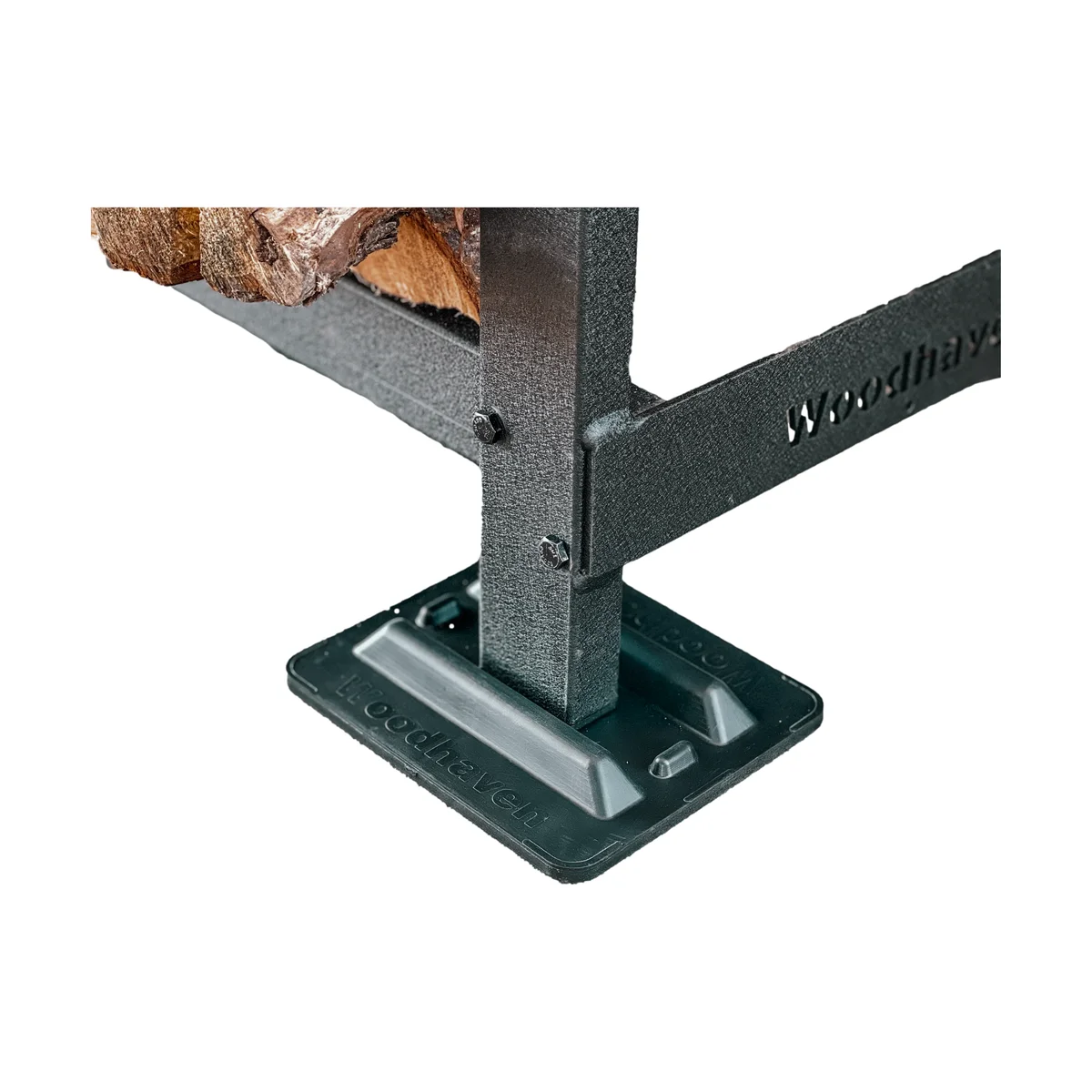 Close-up of the Woodhaven firewood rack's welded steel base joint with engraved Woodhaven branding and black powder-coat finish