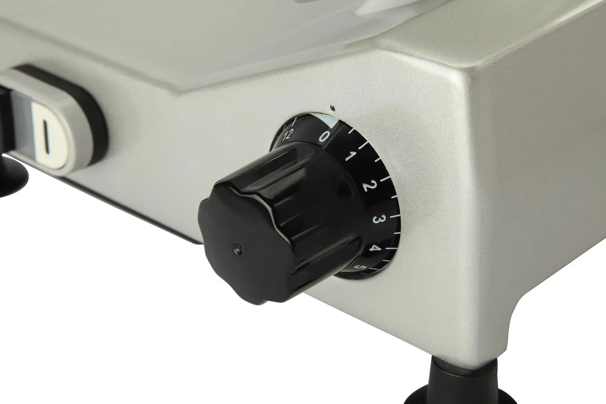 Close-up of the Beswood 10-inch slicer's black slice-thickness dial marked 0 to 12, next to the power switch on the aluminum base