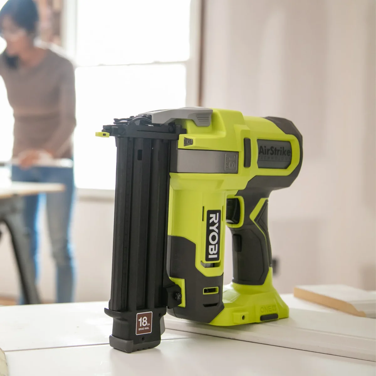 Ryobi AirStrike brad nailer resting on a workbench in a bright workshop, lifestyle in-context shot