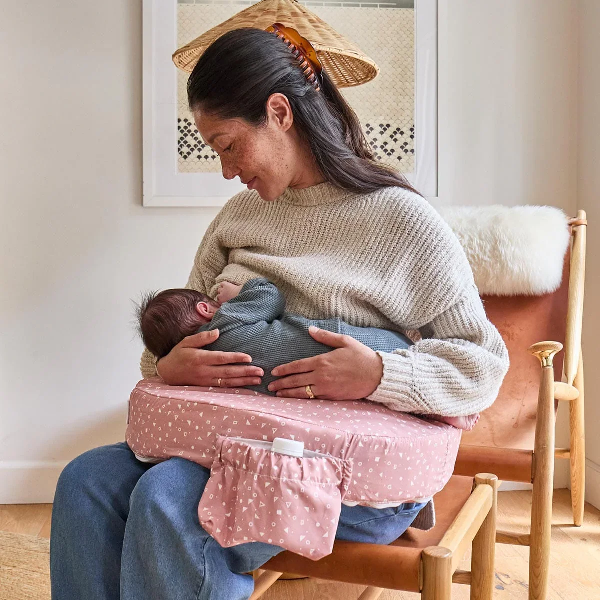 Mother breastfeeding newborn using My Brest Friend Original Nursing Pillow seated in an armchair