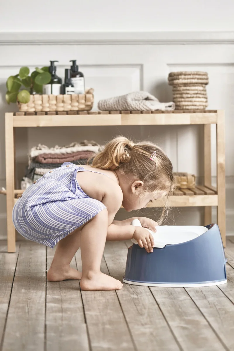 Young child examining BabyBjorn Smart Potty removable inner bowl, bathroom shelf in background