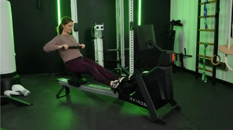Aviron Strong Series rowing machine — person rowing at full back stroke in gym
