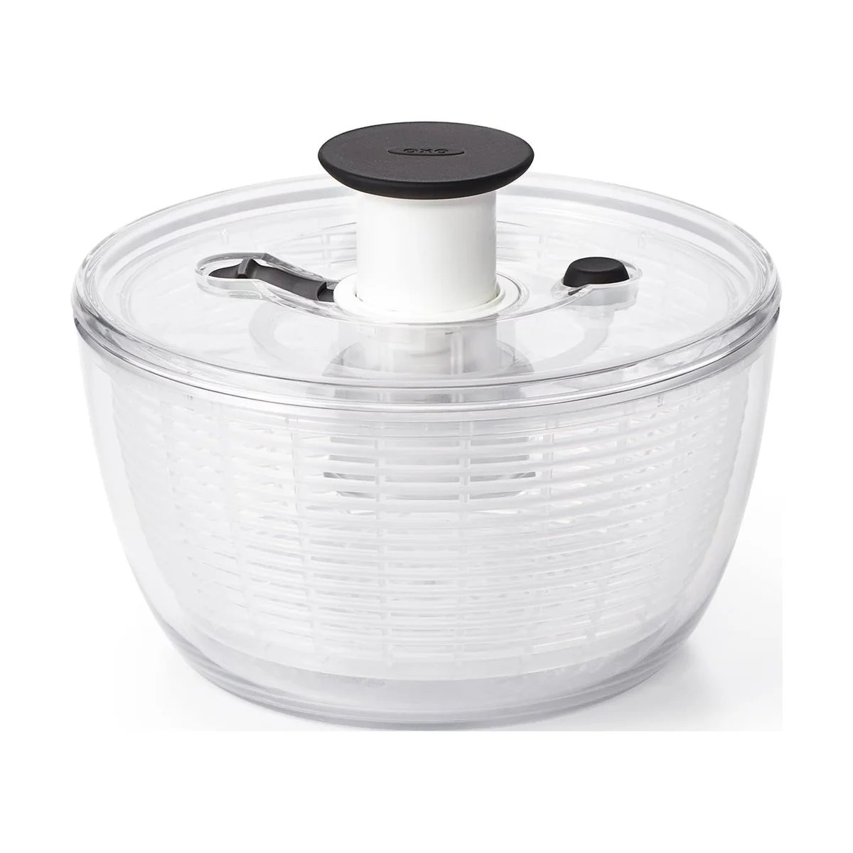 OXO Good Grips Salad Spinner elevated three-quarter view showing the clear lid, black pump knob, brake button and storage lock over the empty clear bowl and basket