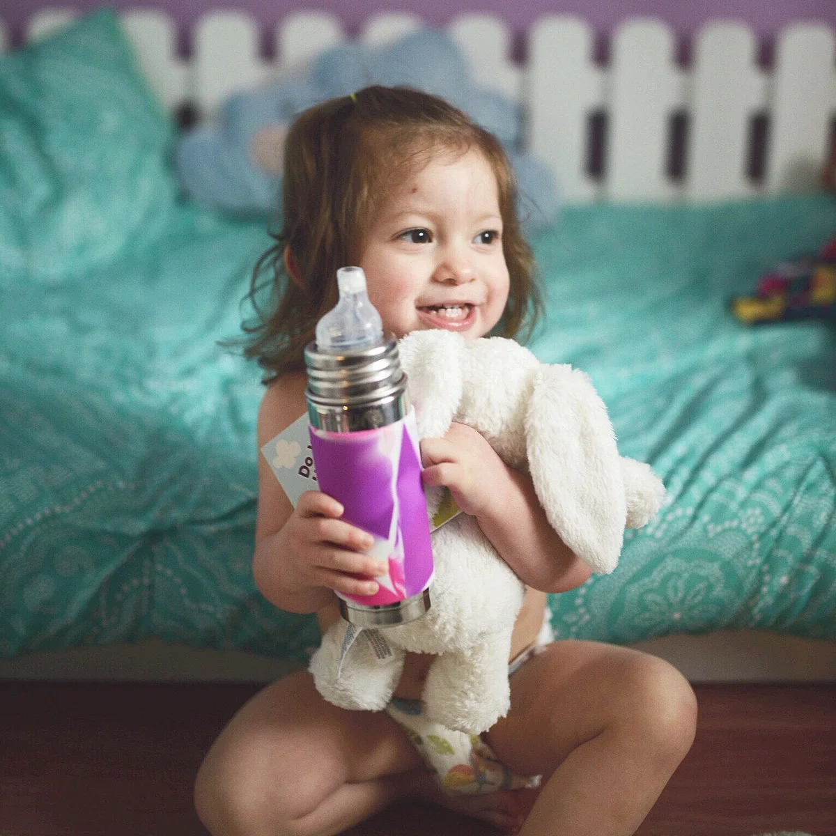 Pura Kiki Insulated Sippy Bottle held by a toddler girl in a lifestyle shot
