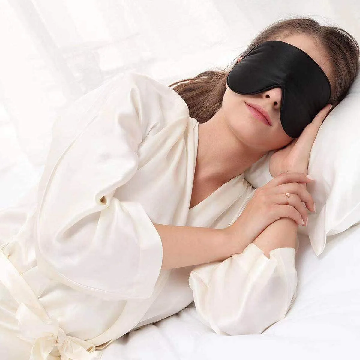 Alaska Bear Natural Silk Sleep Mask worn by a woman resting on a pillow, showing the mask in use for sleep