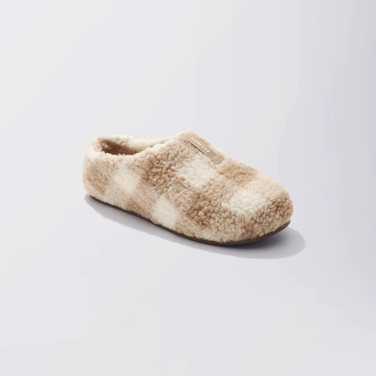 Bombas Sunday Slipper three-quarter angle showing the cushiony sherpa knit checkerboard upper and low-back slip-on collar