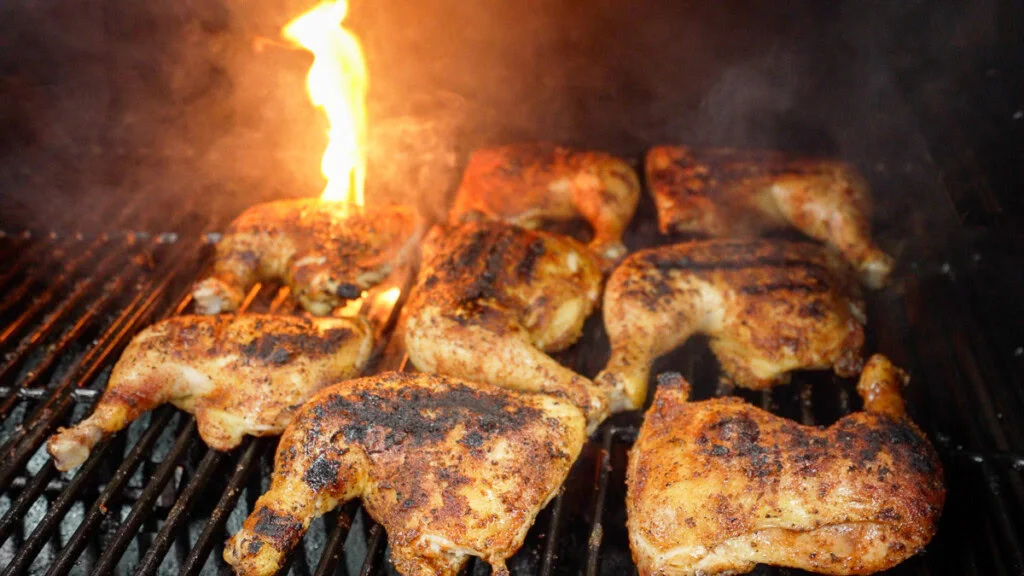 Chicken quarters smoking with visible flame and smoke on the Pit Boss 850 DX's grates, in-use lifestyle shot