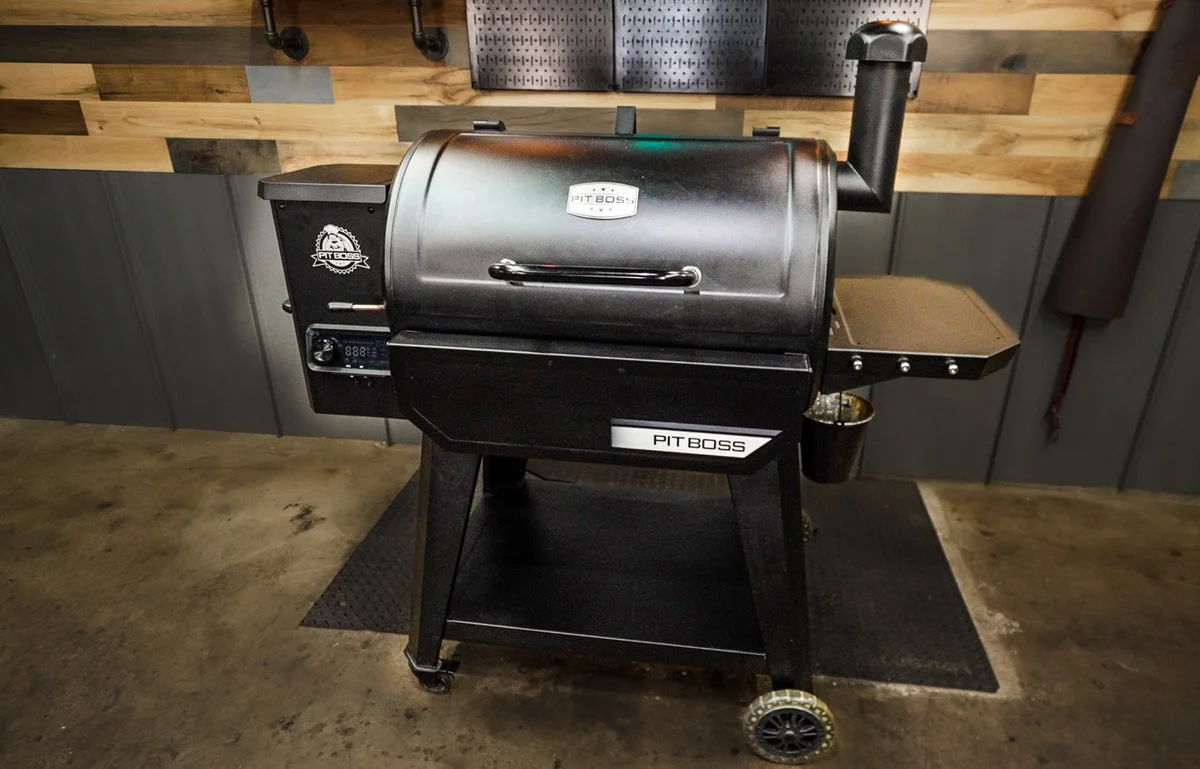 Pit Boss 850 DX Wood Pellet Grill shown at an alternate three-quarter angle in a garage setting, showing hopper, control panel, and side shelf