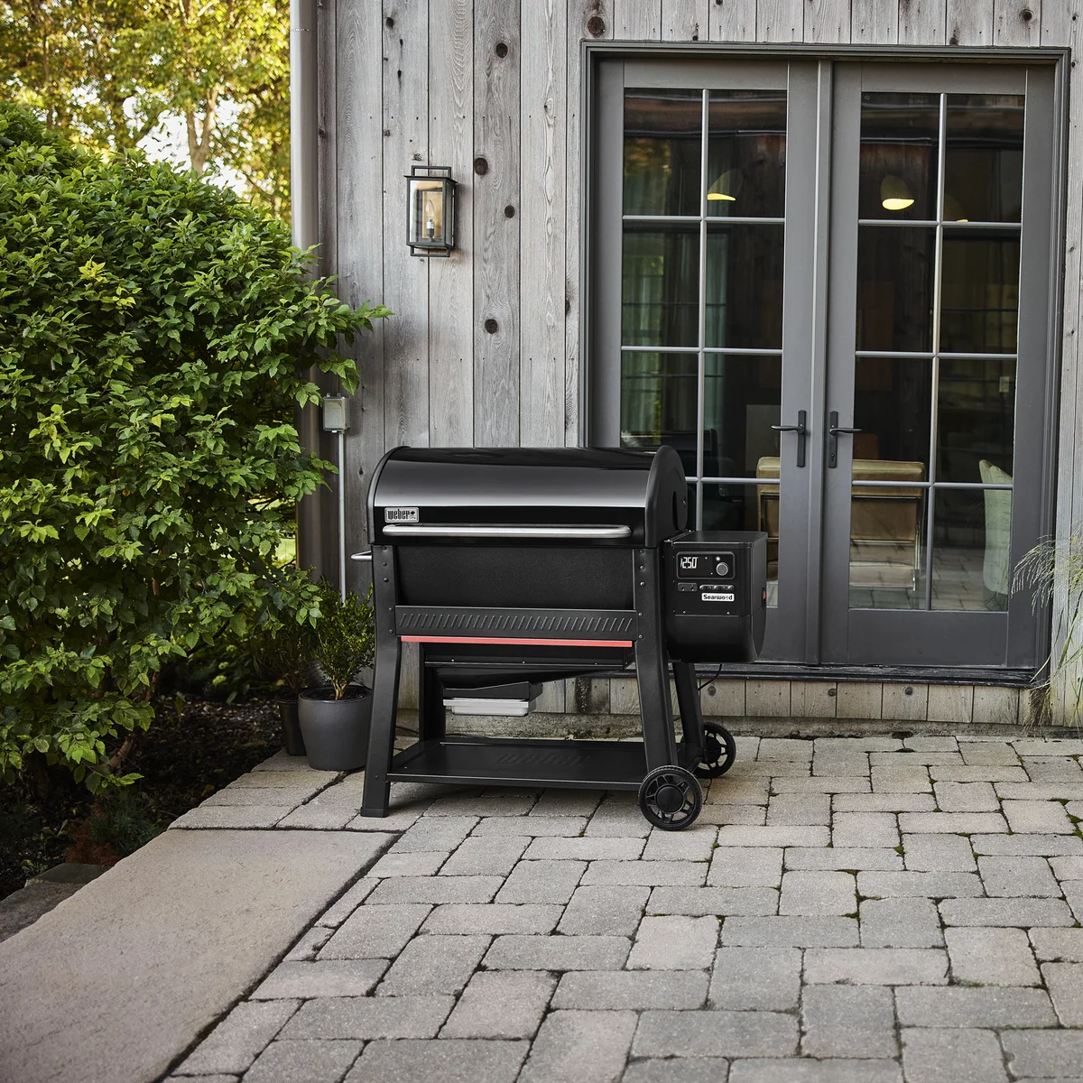 Weber Searwood XL 600 pellet grill in lifestyle setting on a backyard patio next to a house
