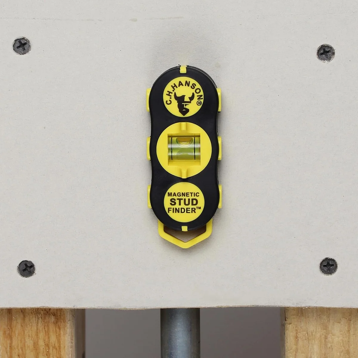 C.H. Hanson magnetic stud finder mounted on drywall between two visible screws, showing in-use stud detection
