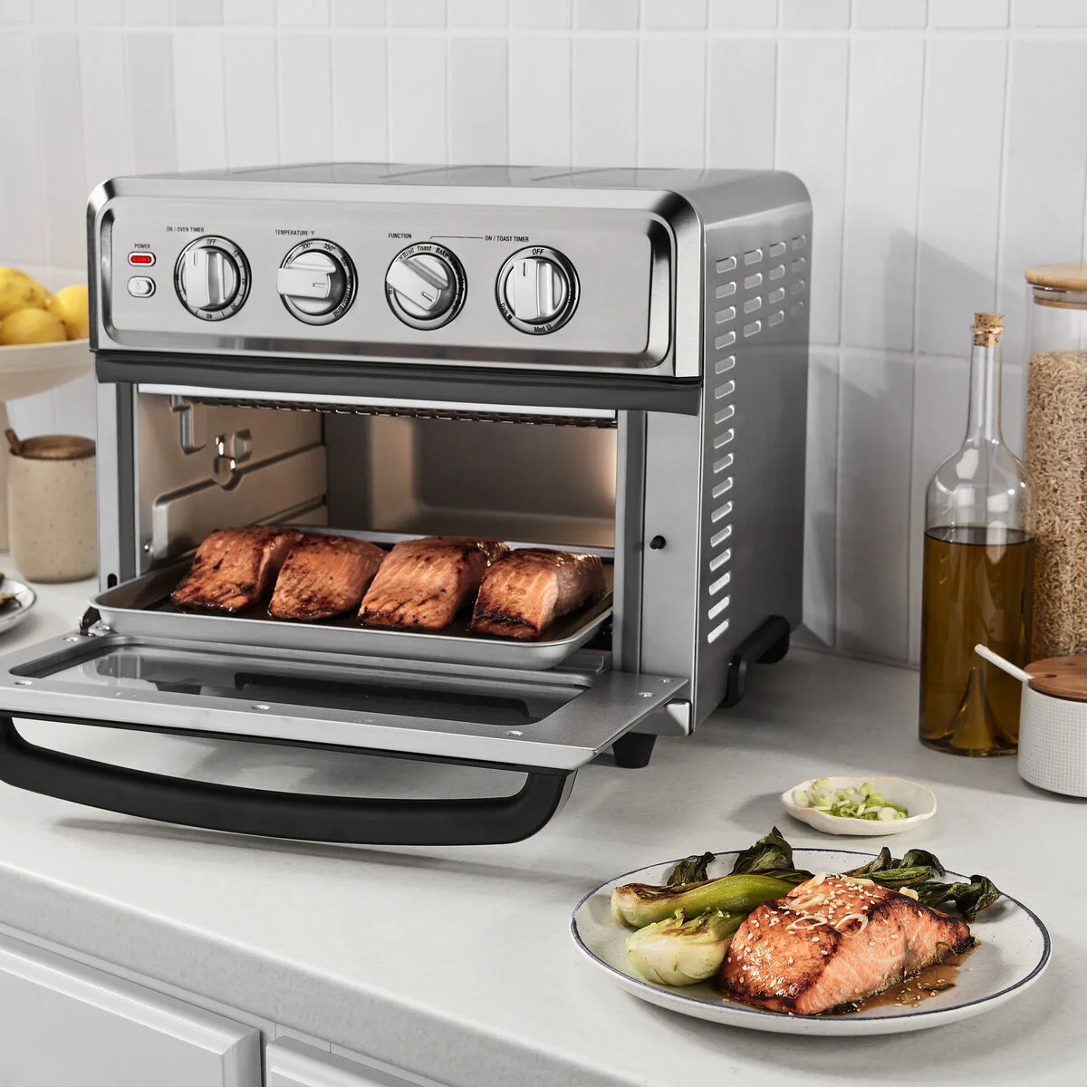 Cuisinart TOA-70 open door at 3/4 angle with salmon broiling on tray, serving plate alongside