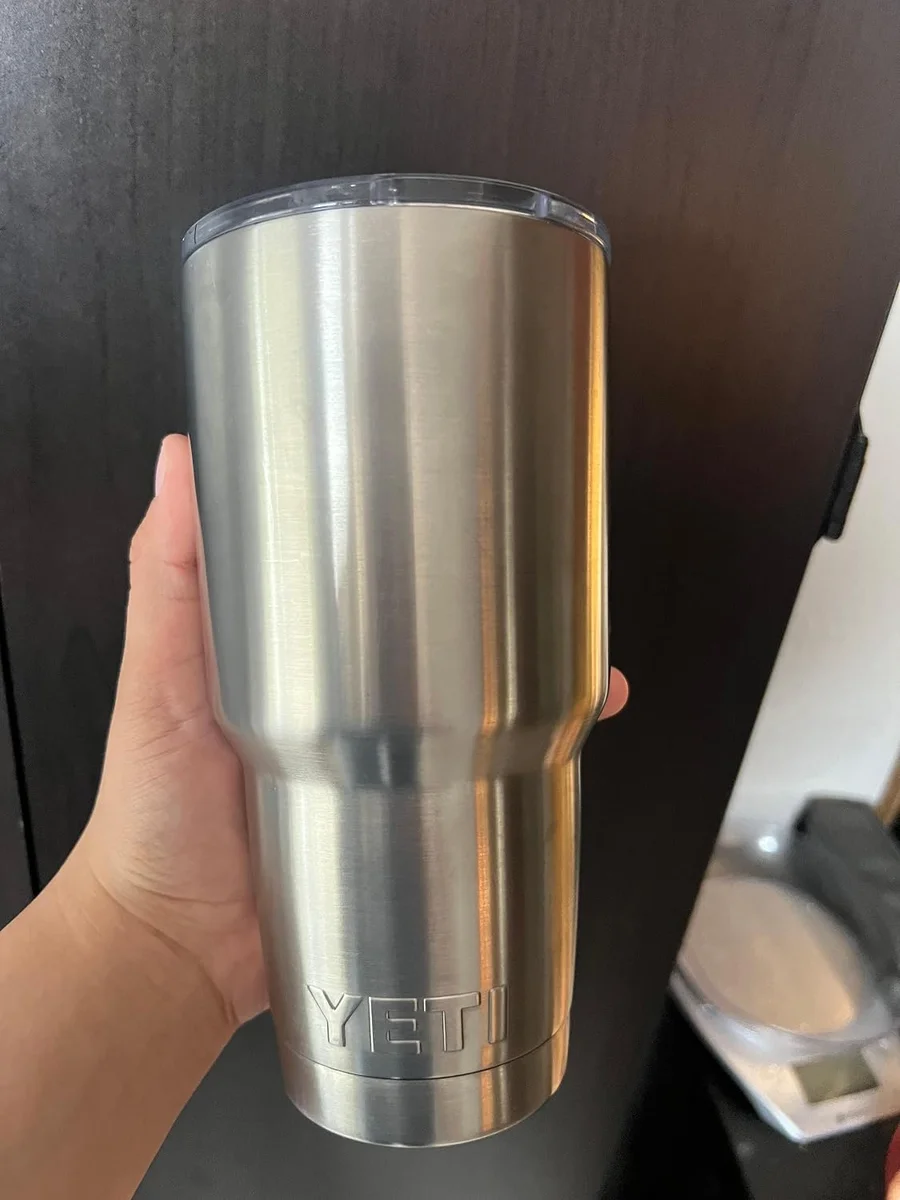 Yeti Rambler 30 oz Tumbler held in hand showing the full stainless steel body, brushed finish, and YETI logo embossed at the base