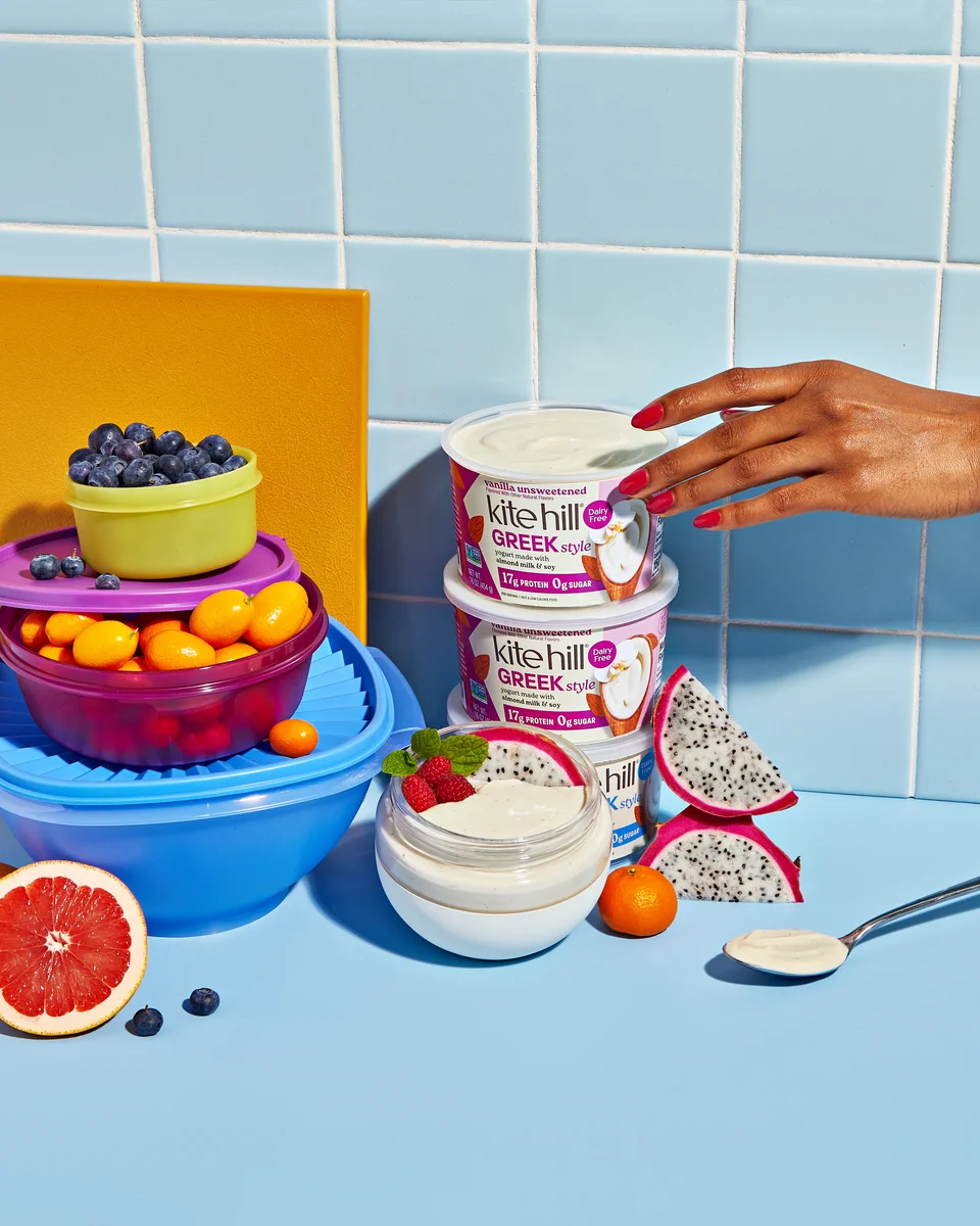 Kite Hill Greek-Style yogurt containers stacked with fresh fruit and a yogurt bowl